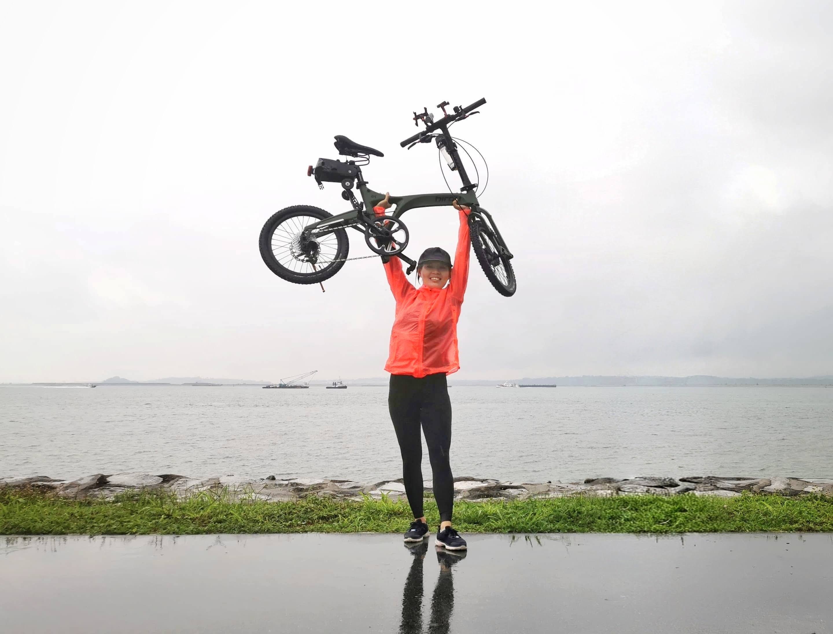 Mayyi, OhmRide's founder and coach, holding up her bicycle by the waterfront in Singapore